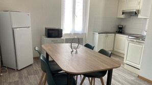 Eine kompakte Küche mit Mikrowelle, Kühlschrank und Essbereich mit Stühlen und Tisch.