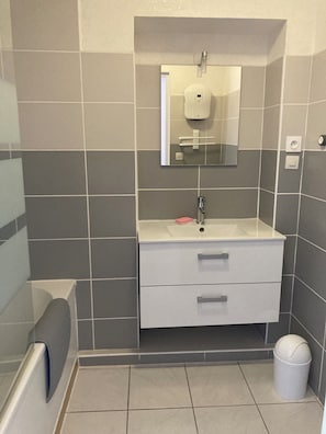 Un bagno con un lavandino bianco, uno specchio e due cassetti.