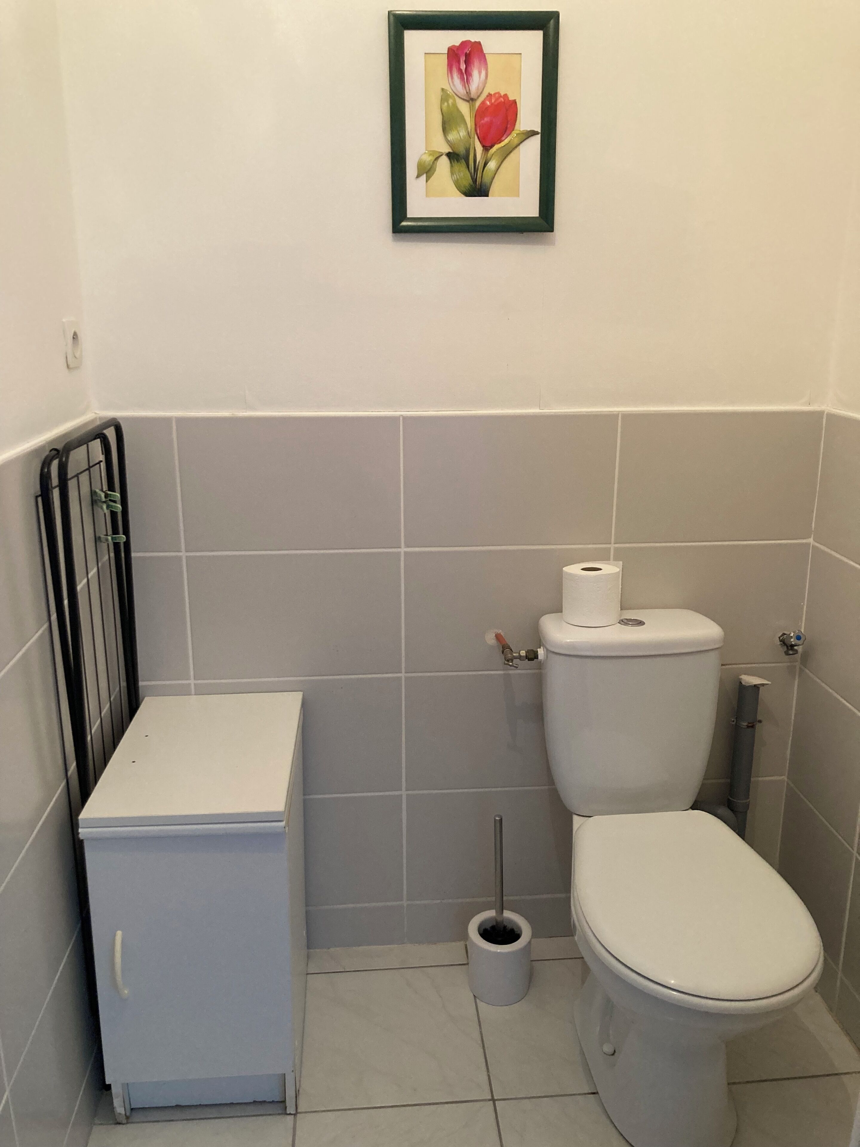 Casa de banho com sanita, bidé e um pequeno armário.