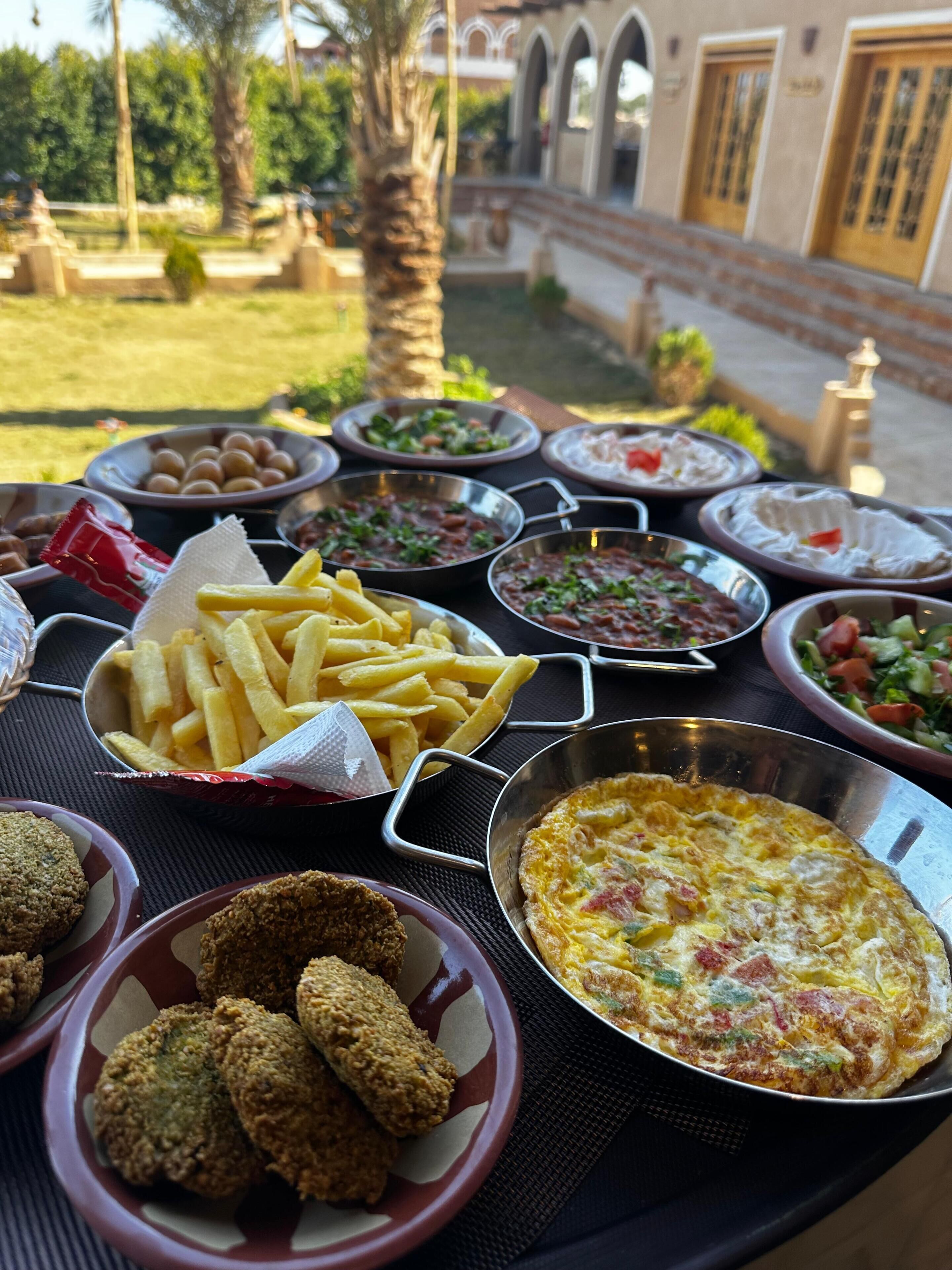 A table with various dishes including fries, salad, and a quiche.