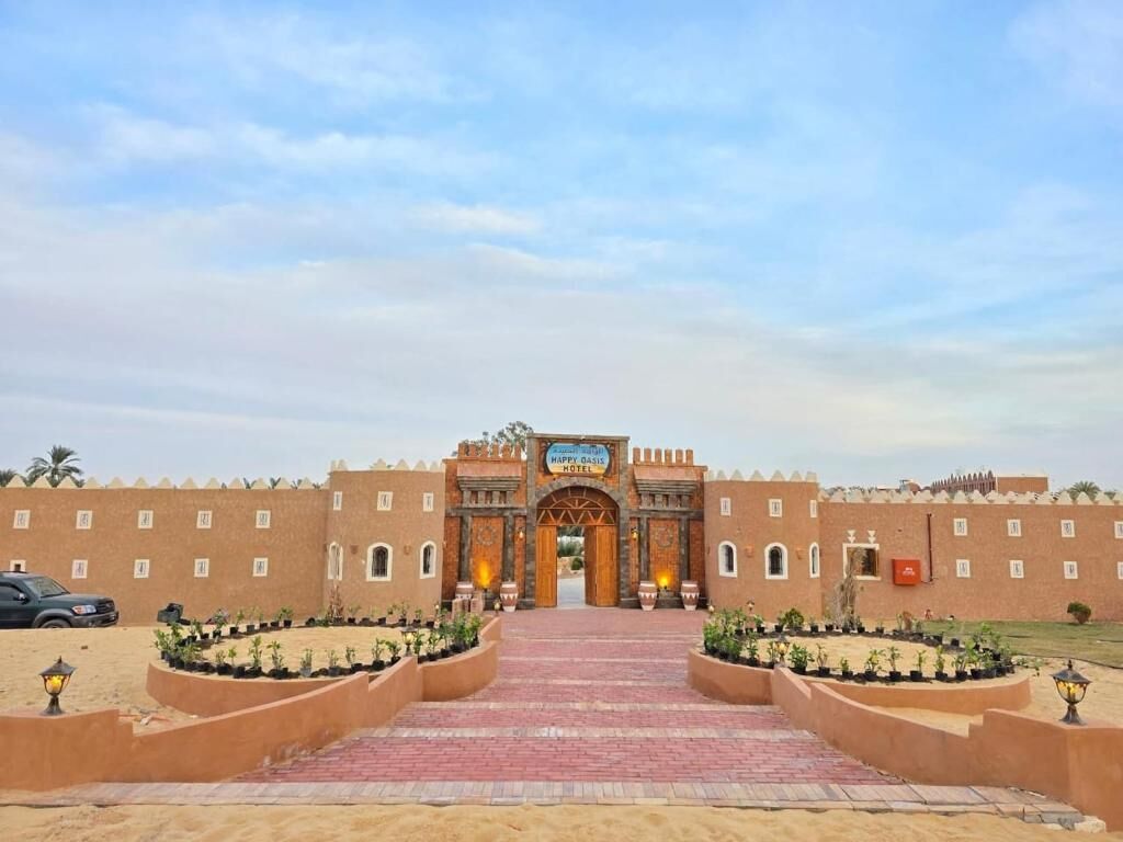 A hotel entrance with a brick facade, a central archway, and a paved walkway leading to the entrance.