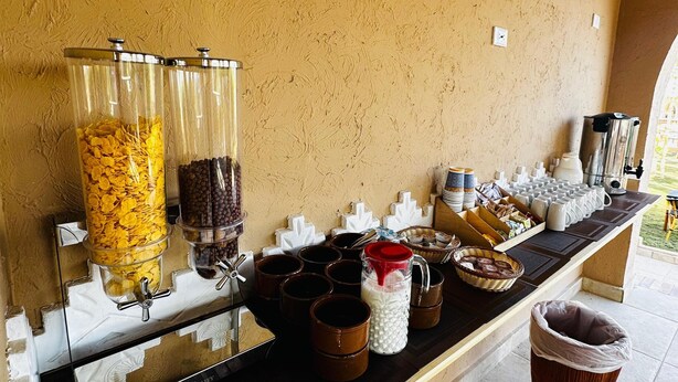 A buffet setup with cereal dispensers, coffee options, and various containers on a counter. - Happy Oasis Hotel (Siwa)