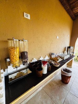 Un montaje tipo buffet con dispensadores de cereales, opciones de café y varios recipientes sobre una barra.