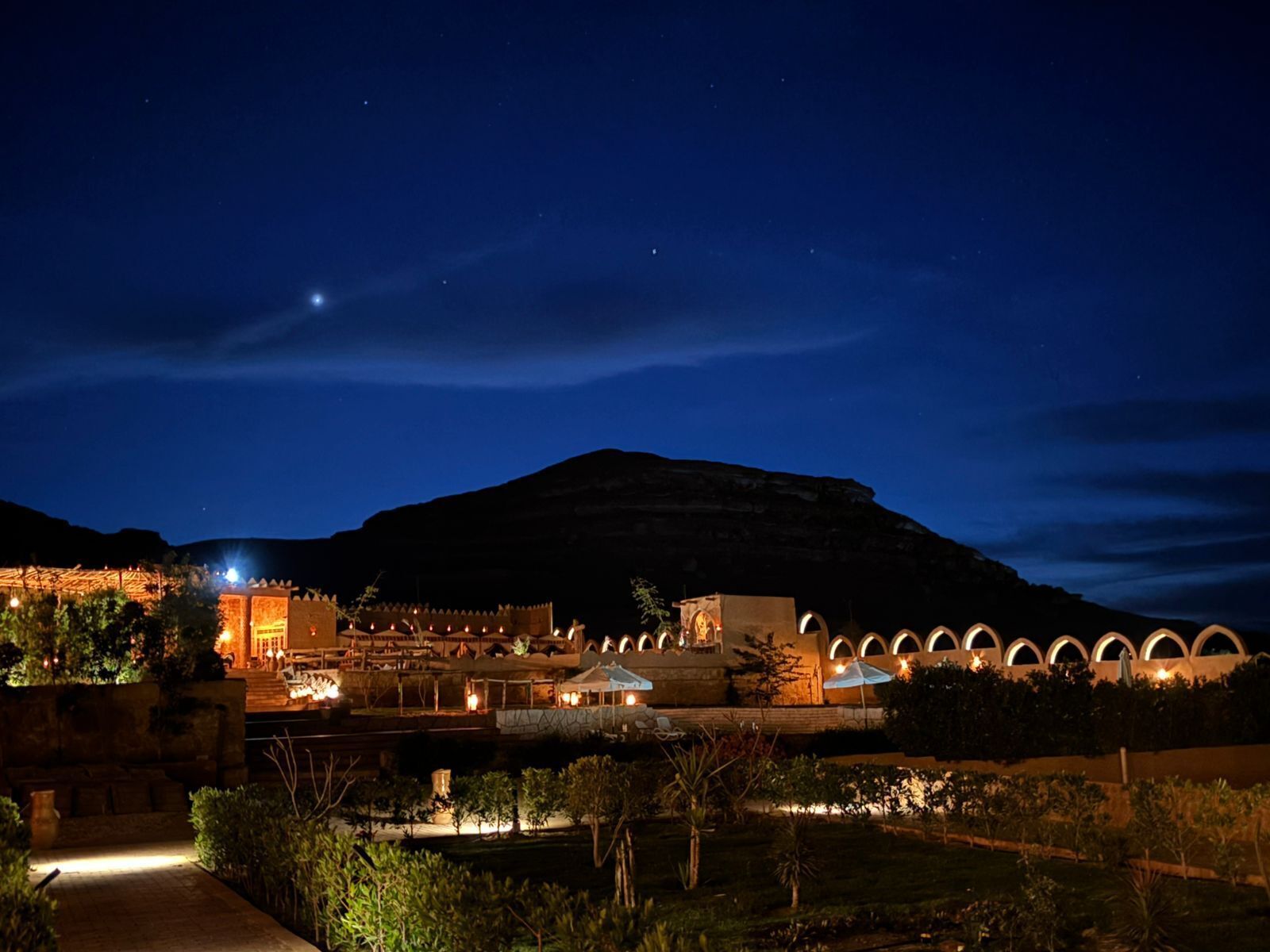 A hotel with a courtyard, arched structures, and a mountain backdrop.
