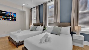 A hotel room with two beds, a TV on the wall, and a window with curtains. - Apartment at 117 Chestnut Philadelphia (Philadelphia)