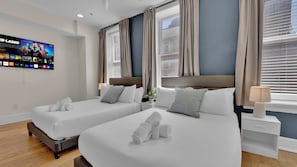 Una habitación de hotel con dos camas, un televisor en la pared y una ventana con cortinas.