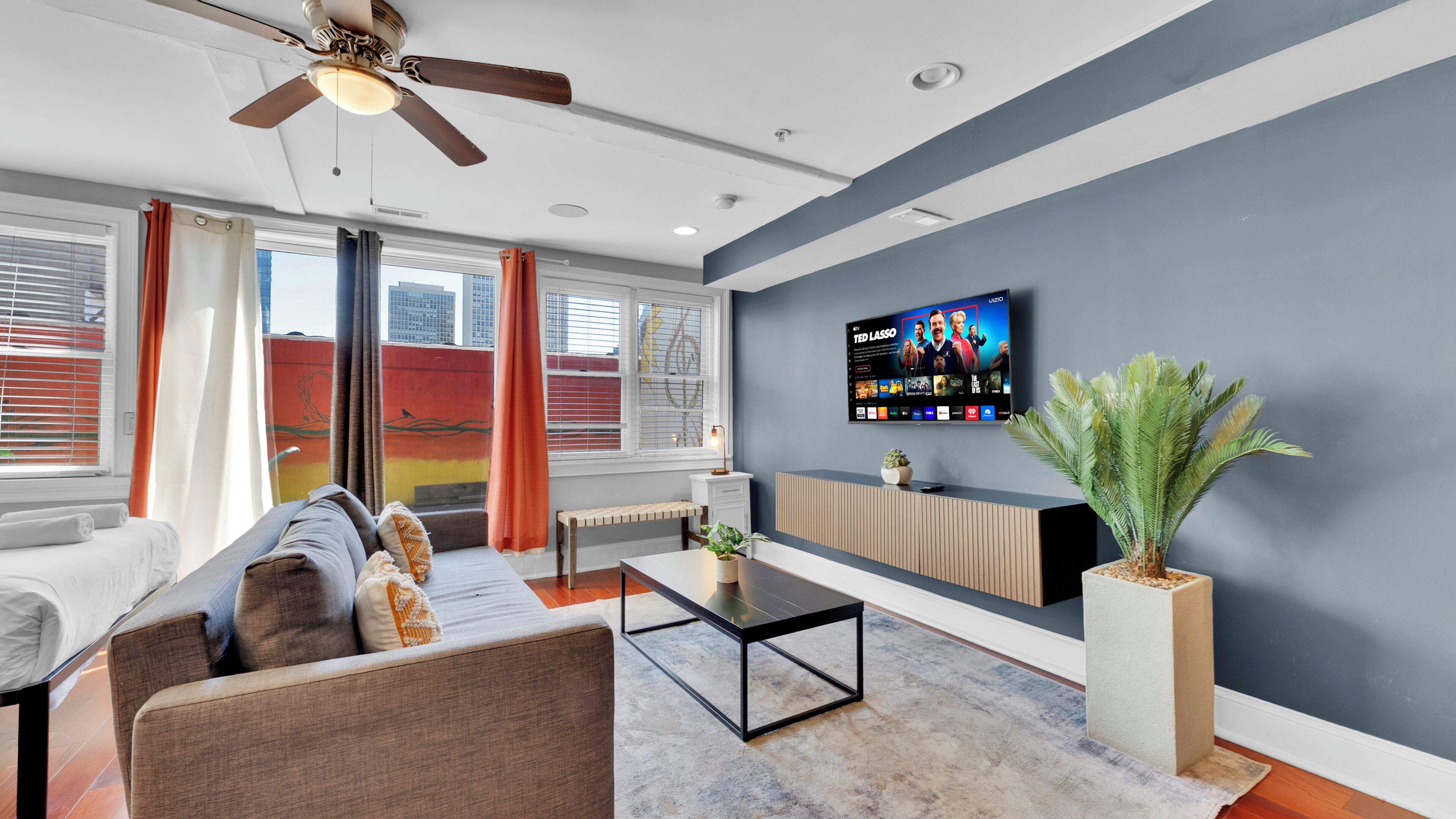 Uma sala de estar moderna com sofá, mesa de centro, TV e uma planta.