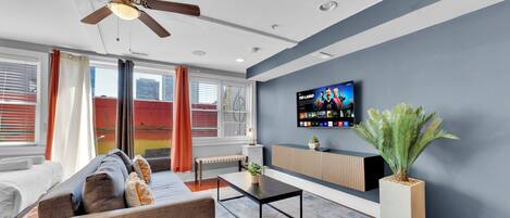 Uma sala de estar moderna com sofá, mesa de centro, TV e uma planta.