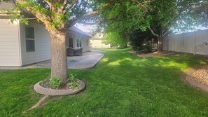 A residential backyard with a lawn, a tree, and a patio area. - Perfect 5-bedroom house in charming Eagle for family, friends and pets. (Eagle)