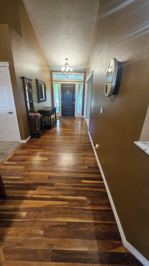 A hallway with wooden flooring, a chandelier, and a door with a circular handle. - Perfect 5-bedroom house in charming Eagle for family, friends and pets. (Eagle)