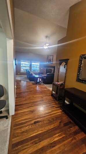 A living room with a fireplace, a ceiling fan, and a large window. - Perfect 5-bedroom house in charming Eagle for family, friends and pets. (Eagle)