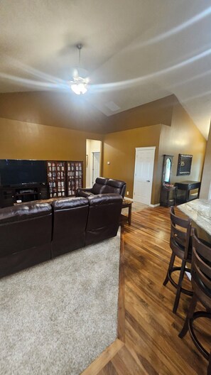 A living room with a sectional sofa, a television, a bookshelf, and a dining area with a table and chairs. - Perfect 5-bedroom house in charming Eagle for family, friends and pets. (Eagle)