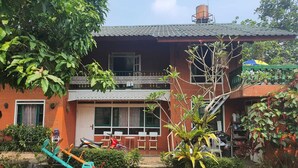 A two-story building with a balcony, a water tank on the roof, and a garden with a swing set. - Cozzy Villa Swasti Cisarua (bogor)