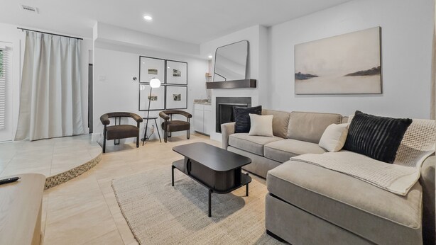 Ein modernes Wohnzimmer mit Sofa, Couchtisch und Sesseln, einem Kamin und einem großen Bild an der Wand.
