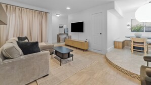 Ein modernes Wohnzimmer mit einer Couch, einem Couchtisch und einem Flachbildfernseher.