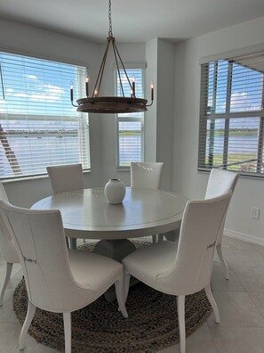 A dining area with a round table, white chairs, and a chandelier. - PRISTINE CONDO, 1st floor, 2 bed/2 bath, Golfers PARADISE at Calusa Country Club (Lakewood Ranch)