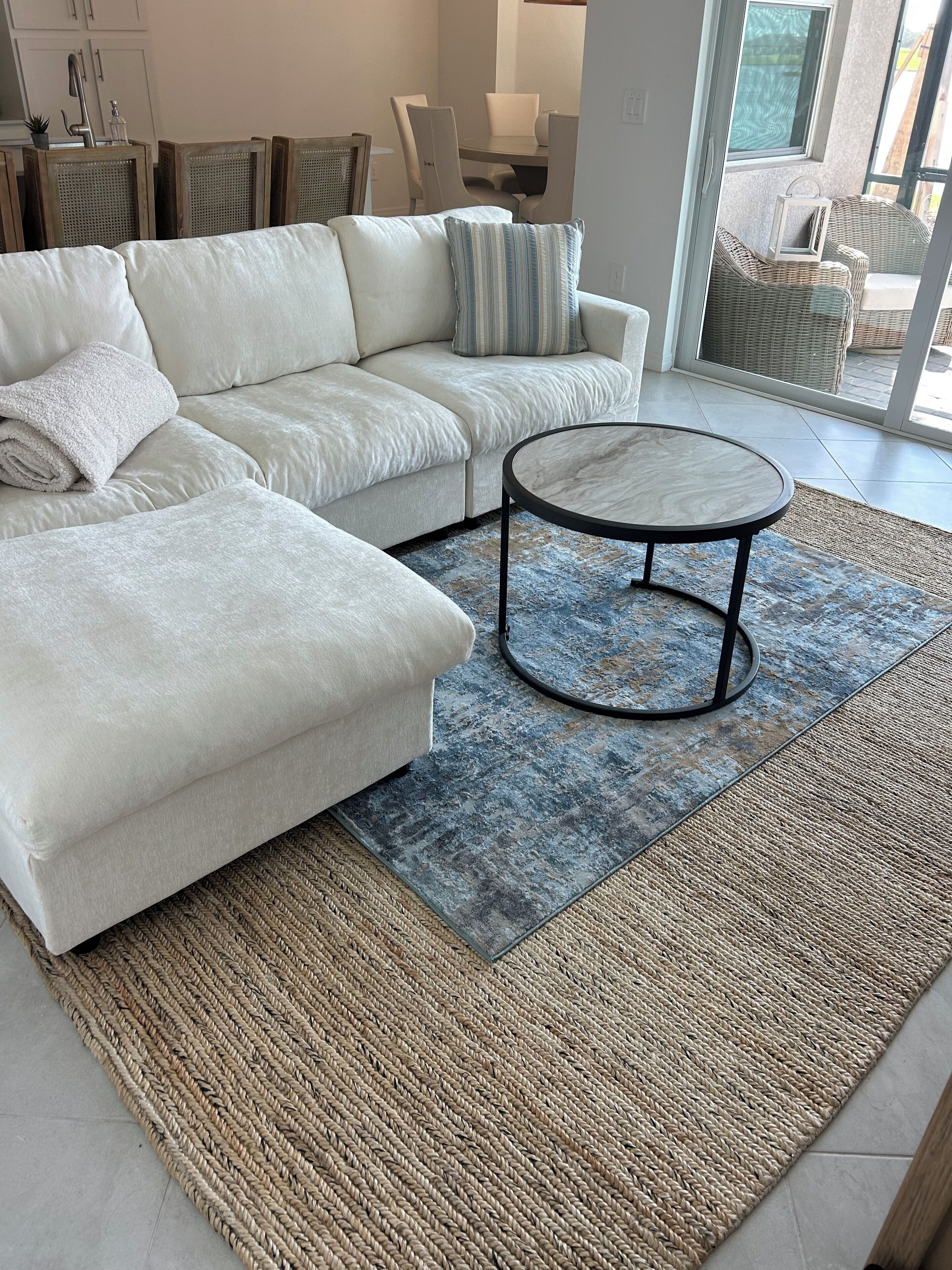 A modern living room with a sectional sofa, a round coffee table, and a woven rug.