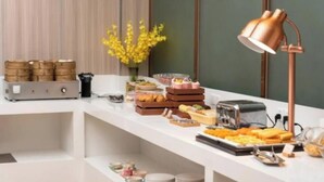 A buffet setup with various food items, a coffee machine, and a copper lamp. - Vienna Hotel Guangzhou North Station (Guangzhou)
