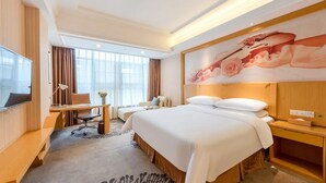 A hotel room with a bed, a desk, a chair, a TV, and a large window. - Vienna Hotel Guangzhou North Station (Guangzhou)