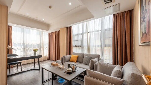 A modern living room with a sofa, coffee table, and dining area. - Vienna Hotel Guangzhou North Station (Guangzhou)
