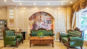A lobby with a green sofa set, a wooden coffee table, and a mural on the wall. - Vienna Hotel Guangzhou North Station (Guangzhou)