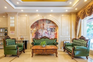 A lobby with a green sofa set, a wooden coffee table, and a mural on the wall. - Vienna Hotel Guangzhou North Station (Guangzhou)