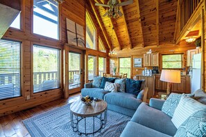 A log cabin interior with a living room, kitchen, and large windows. - Chic Boho~Private Mtn View Cabin~Hottub & 2 Kings (Sevierville)