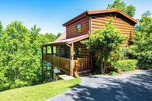 Eine Blockhütte mit Veranda, umgeben von Bäumen.