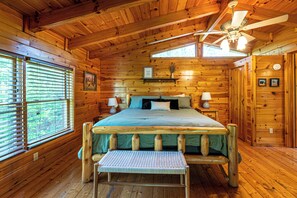 Ein Schlafzimmer in einer Holzhütte mit Bett, Bank, Deckenventilator und Jalousien.