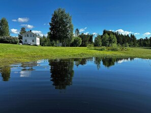 Ein Haus mit großem Rasen und einem Teich, der den Himmel spiegelt.