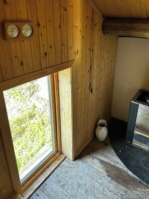 Ein Holzinnenraum mit einem Fenster, einem Thermometer und einem Wasserkocher.