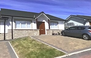 Ein zweigeschossiges Haus mit Eingangstür, Auffahrt und geparktem Auto.