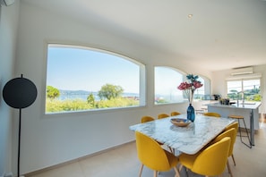 A modern dining area with a large table, yellow chairs, and a view of the outdoors.