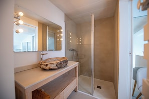 A modern bathroom with a glass shower enclosure, a wooden vanity, and a large mirror with lights. - Villa Joia 2 Saint Tropez (Gassin)