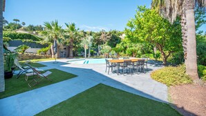 Un patio trasero con piscina, mobiliario de jardín y una mesa de comedor.