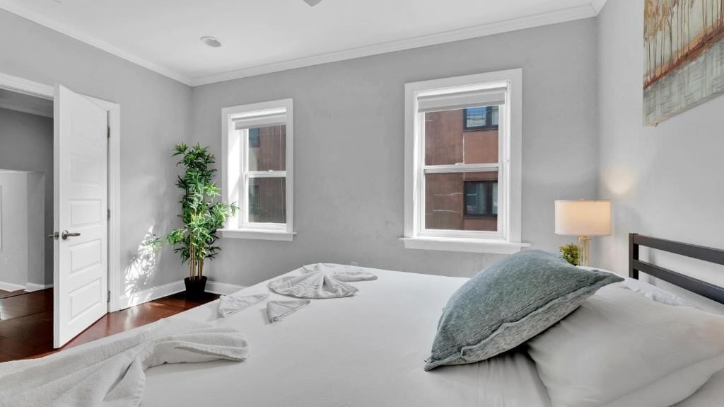 Une chambre à coucher avec un lit, une plante en pot, une lampe et une vue sur l’extérieur.