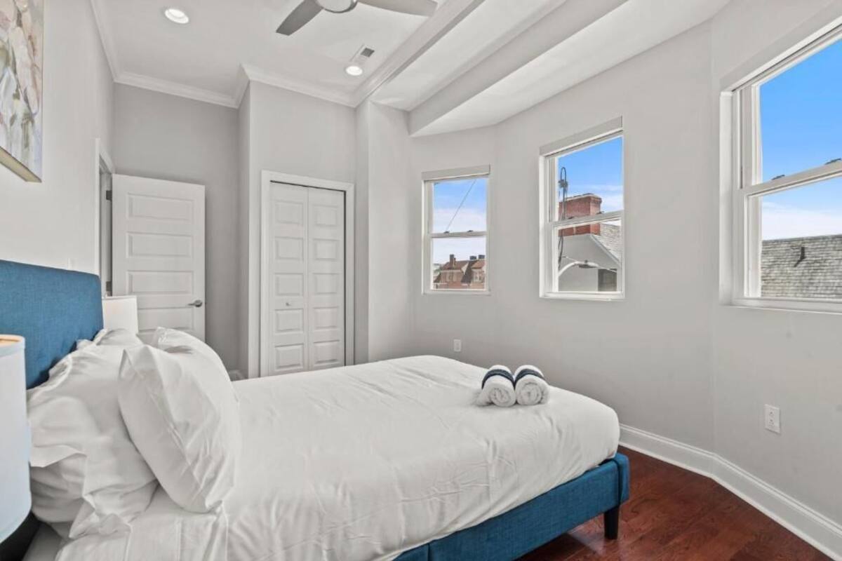 A bedroom with a bed, a ceiling fan, a window, and a door.