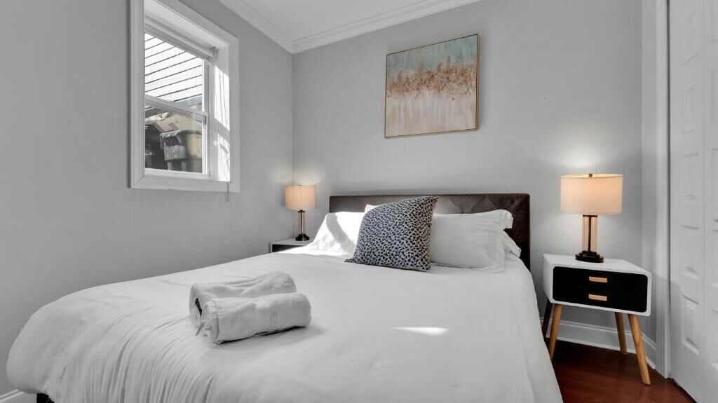 Une chambre à coucher avec un grand lit, deux tables de chevet, une fenêtre et un tableau au mur.