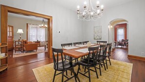 A dining area with a wooden table and chairs, a chandelier, and a mirror reflecting the room. - Charming & Updated 1867 Brick House in Historic Downtown Delaware, OH; Sleeps 12 (Delaware)