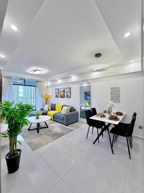 Una sala de estar moderna con sofá, mesa de comedor, sillas y un ventanal grande.