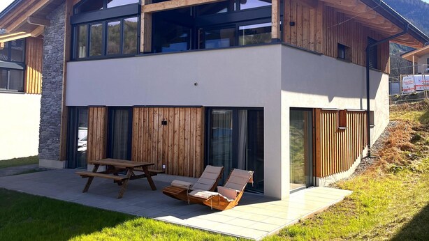 A modern two-story house with a stone facade, wooden beams, and large windows. - Modern Holiday Home With Sauna (Sankt Lambrecht)