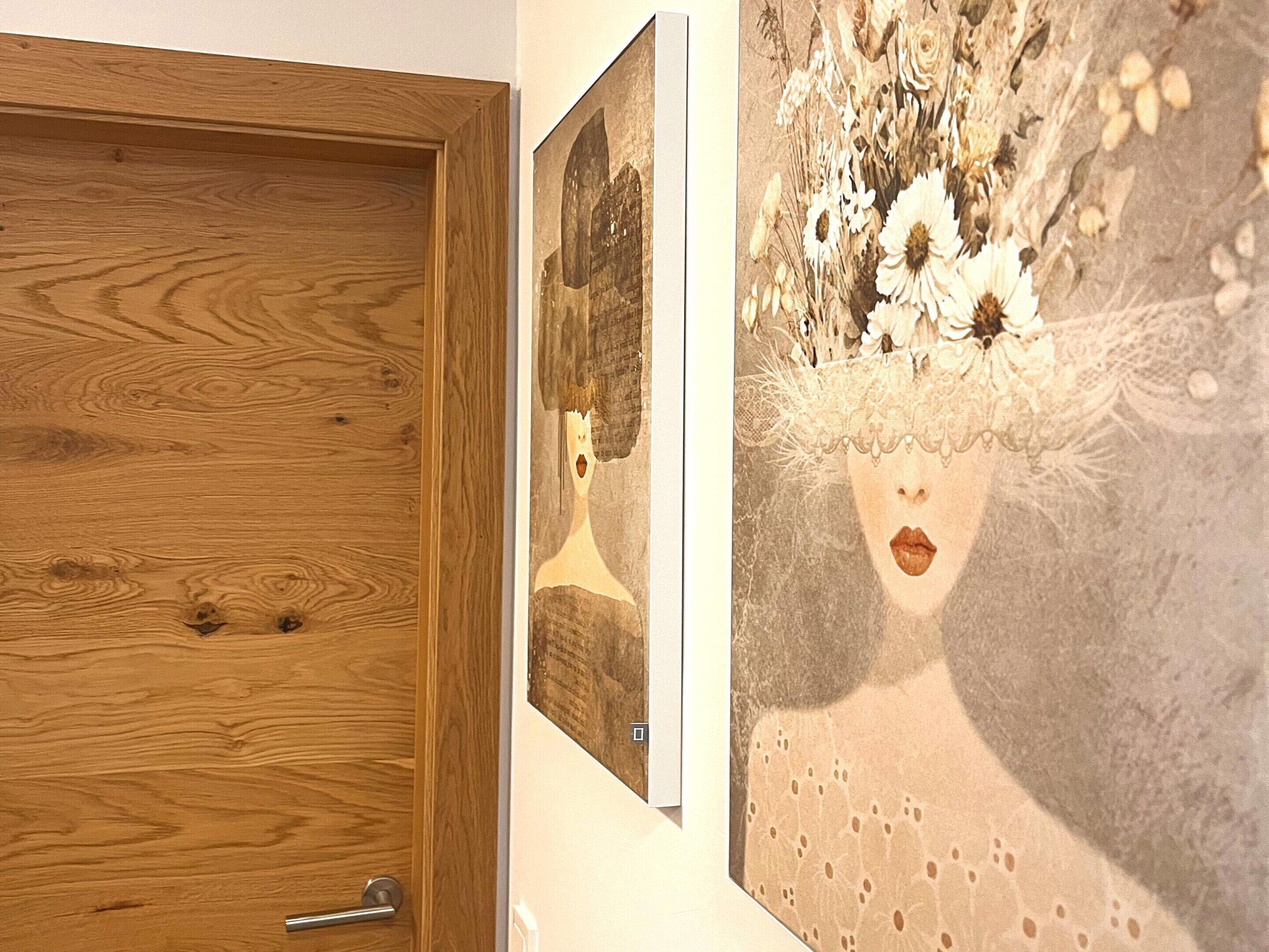 Una puerta de madera con un picaporte metálico y una pared con dos cuadros enmarcados.