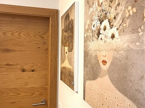 Eine Holztür mit einem Metallgriff und eine Wand mit zwei gerahmten Kunstwerken.
