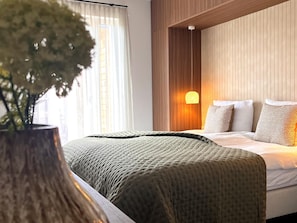 Ein modernes Hotelzimmer mit einem Bett, einer Nachttischlampe und einem Blumentopf.