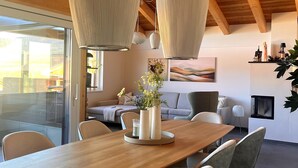 A modern dining area with a wooden table, grey upholstered chairs, a vase with flowers, and pendant lights. - Modern Holiday Home With Sauna (Sankt Lambrecht)