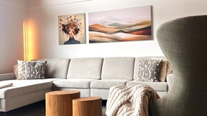 A modern living room with a sectional sofa, two wooden side tables, and a large armchair. - Modern Holiday Home With Sauna (Sankt Lambrecht)