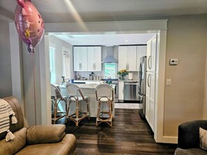 A modern kitchen with white cabinets, a stainless steel refrigerator, and a dining area with wicker chairs. - Perfect 2-bedroom house with AC in quaint Decatur (Decatur)