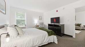 Une chambre à coucher comprenant un lit, un bureau, une chaise, un téléviseur et une armoire.