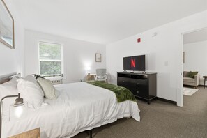 Ein Schlafzimmer mit Bett, Schreibtisch, Stuhl, Fernseher und Kleiderschrank.