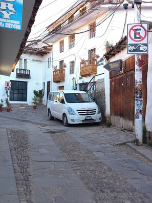 Ein weißer Van geparkt in einer Kopfsteinpflasterstraße in einer europäischen Stadt, mit Gebäuden, die Balkone und Holzhinterfenster haben.